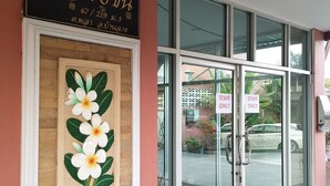 A building entrance with a sign in a foreign language, a framed picture of flowers, and glass doors with 'STAFF ONLY' signs. - Areechon Apartment (Ban Chang)