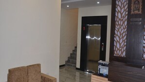 Un espace d’accueil comprenant un comptoir de réception, un coin salon et un escalier menant à un ascenseur.