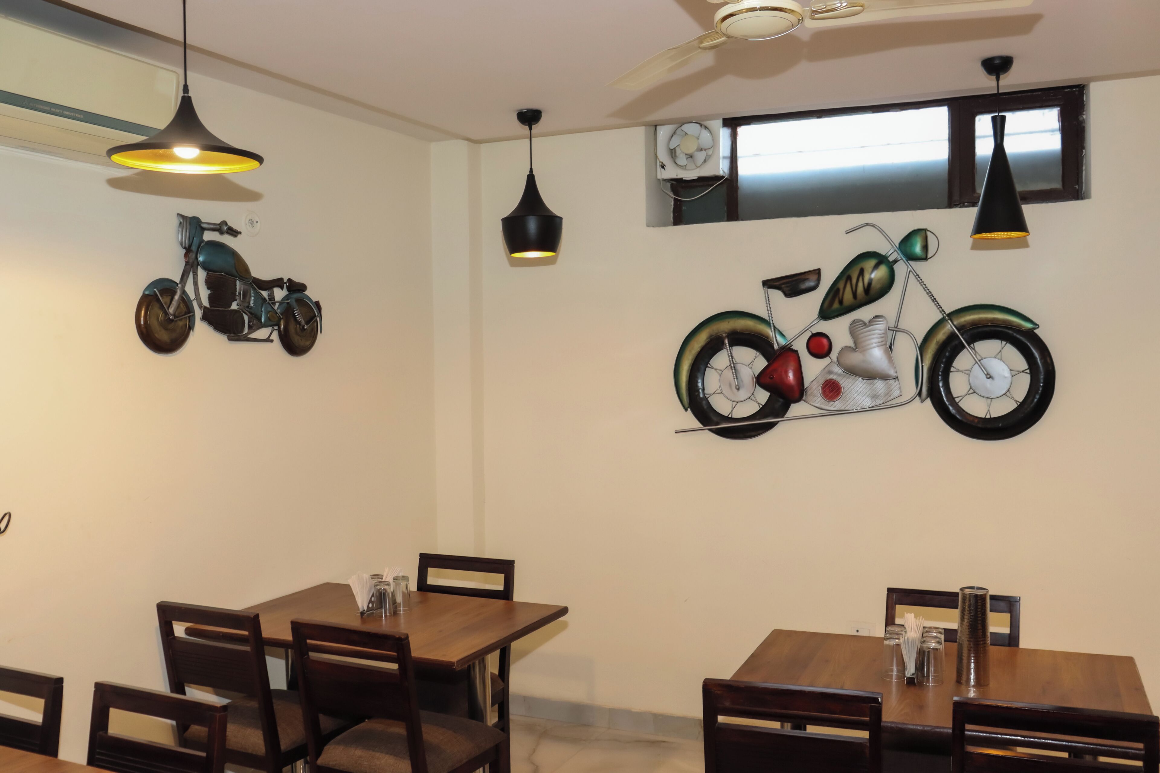 Un espace repas avec des tables et des chaises en bois, des luminaires suspendus et des décorations murales, dont une moto.
