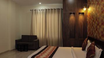 A hotel room with a bed, a sofa, a small table, and a curtain.