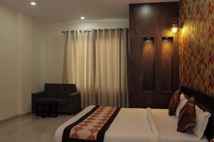 Una habitación de hotel con una cama, un sofá, una mesita y una cortina.