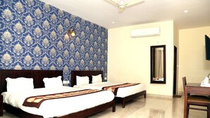Une chambre d’hôtel avec deux lits en bois, un ventilateur de plafond et un grand miroir.