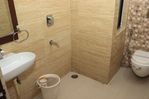 Un baño con lavamanos, inodoro, ducha y un cubo.