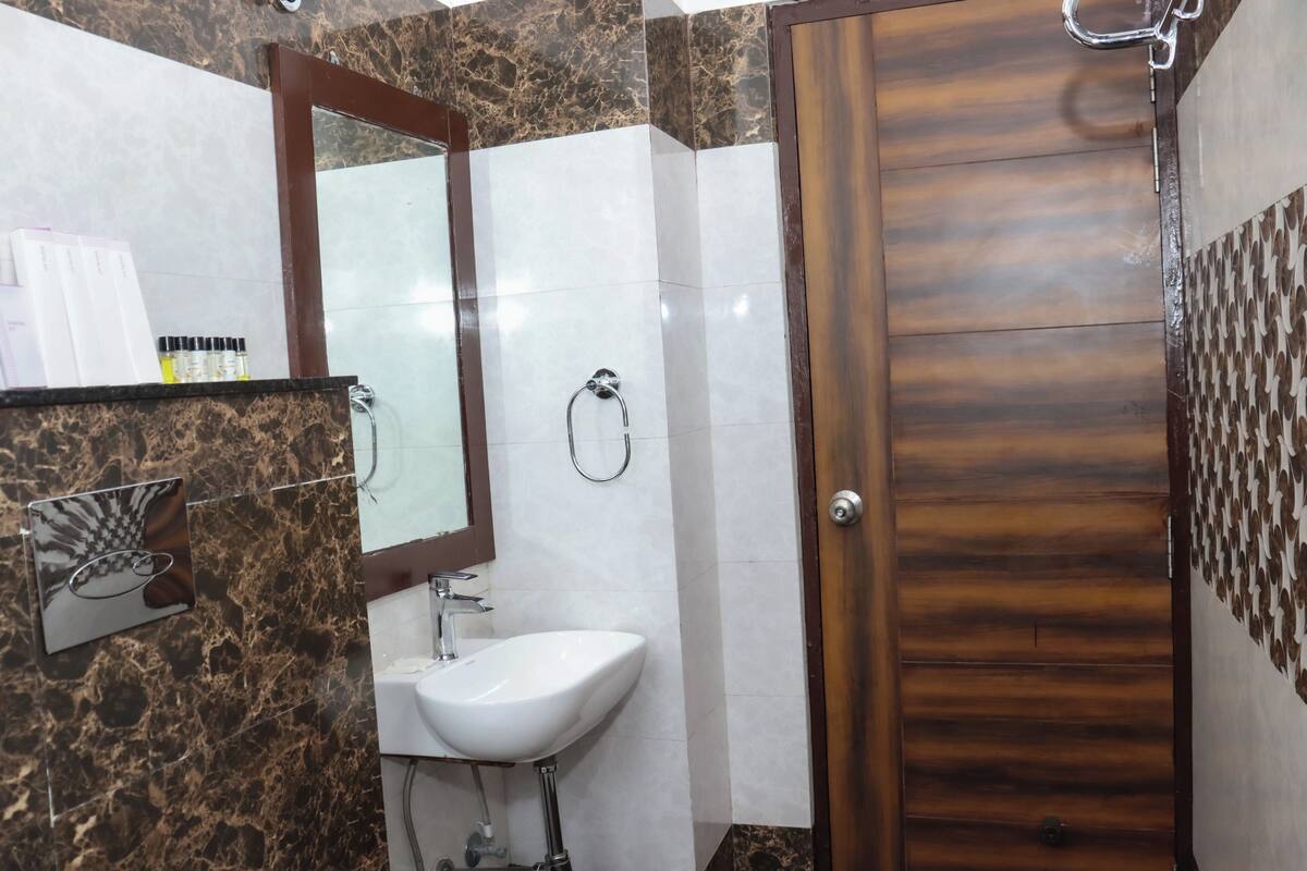 Un baño con lavamanos de mármol, un espejo y una puerta de madera.