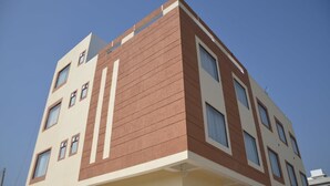 Un immeuble à plusieurs étages doté d’une architecture moderne, caractérisé par une combinaison de couleurs beige et marron, et de nombreuses fenêtres à chaque étage.
