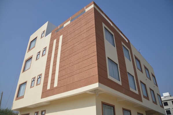 A multi-story building with a modern architectural design, featuring a combination of beige and brown colors, and multiple windows on each floor. - Hotel The Grand Kukas (Amer)