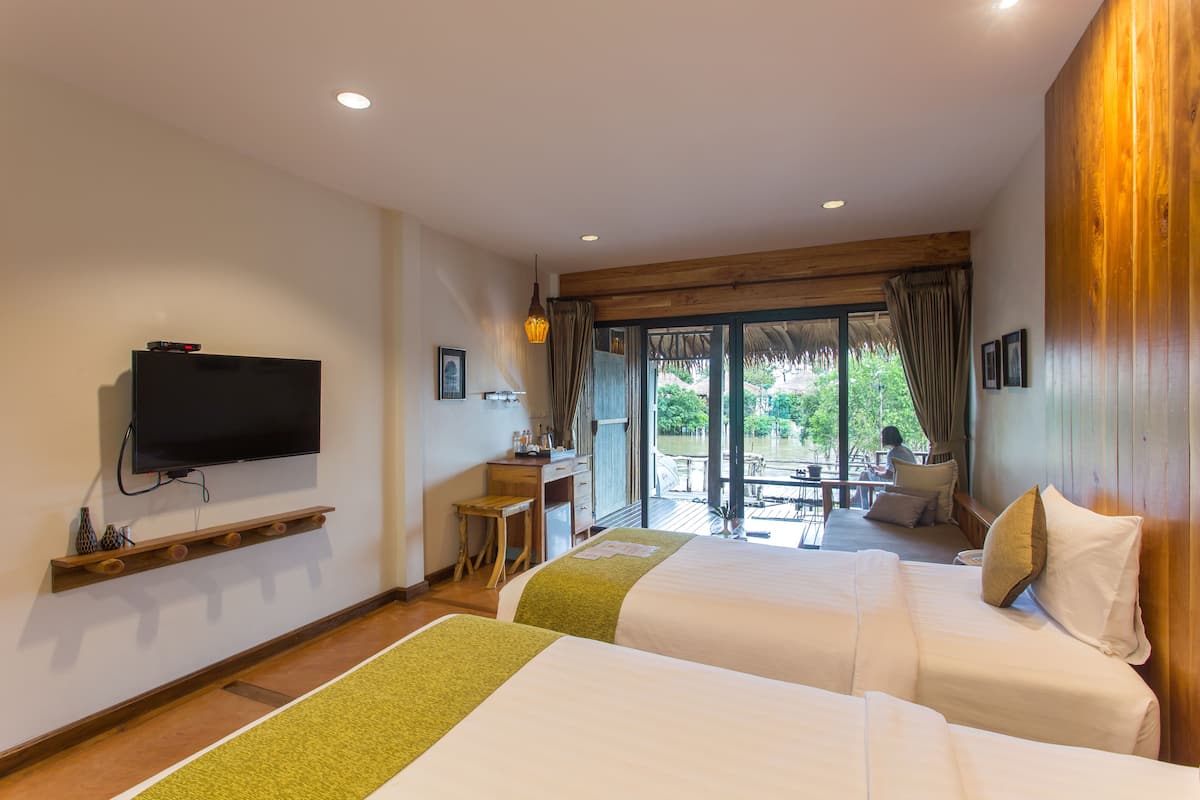 A hotel room with two beds, a TV, a desk, and a view of the outdoors.