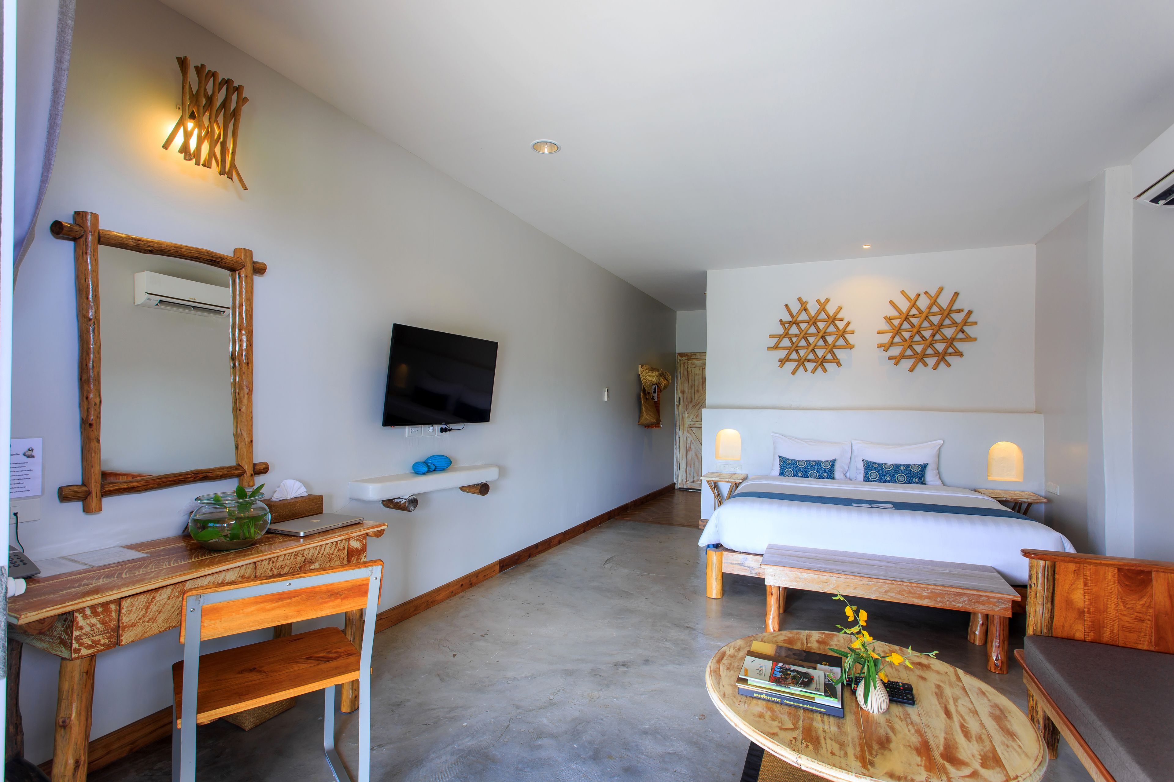 A modern hotel room with a large bed, a wooden desk, a television, and decorative wall art.