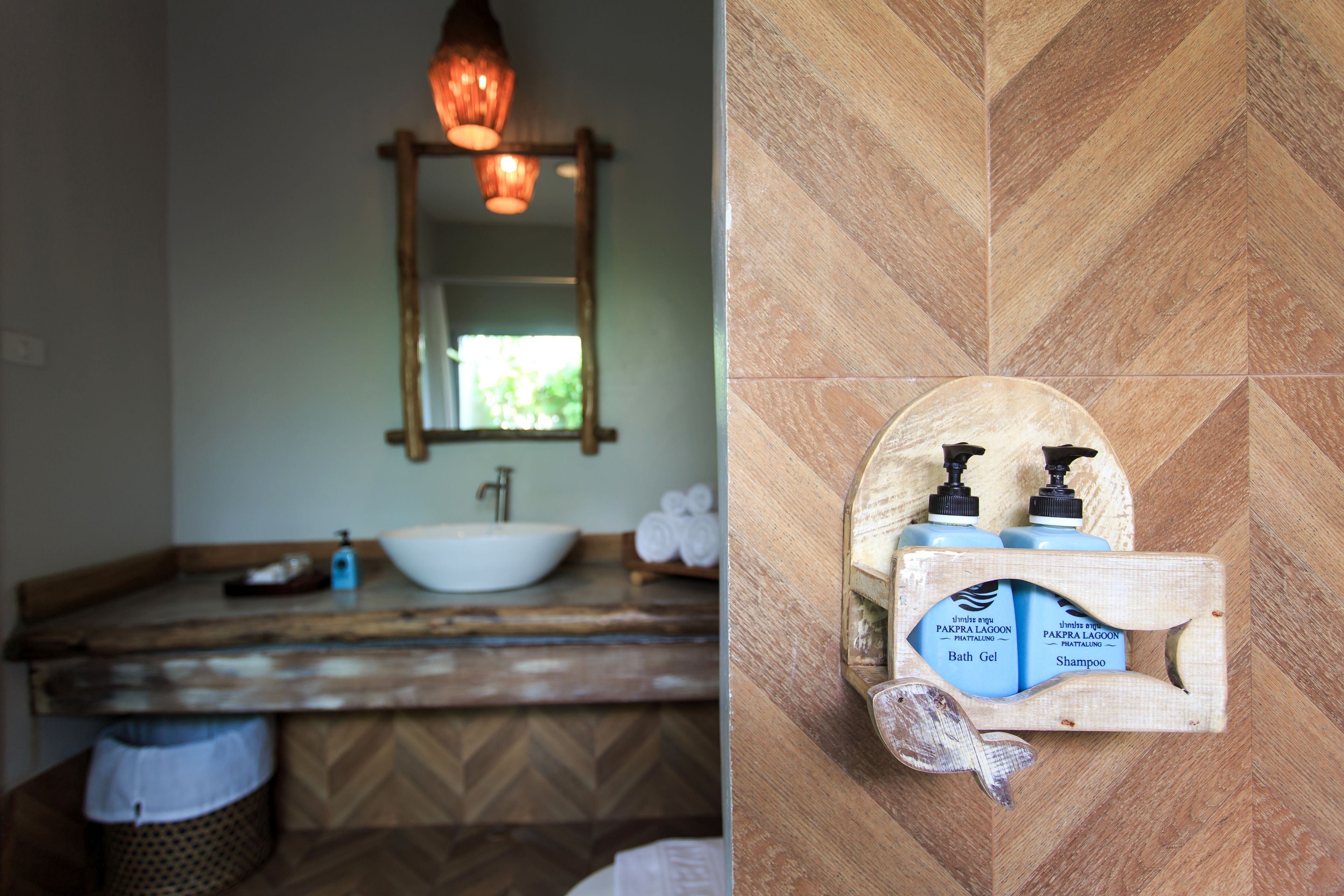 Un bagno con un mobile vanitario in legno, un lavandino bianco e uno specchio. Si nota uno scaffale con prodotti da bagno.