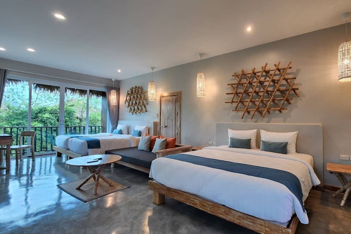 A modern hotel room with a large bed, a smaller bed, a balcony, and a dining area.