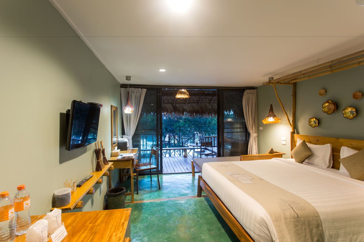 A hotel room with a bed, a desk with a computer, a TV, and a view of the outdoors.
