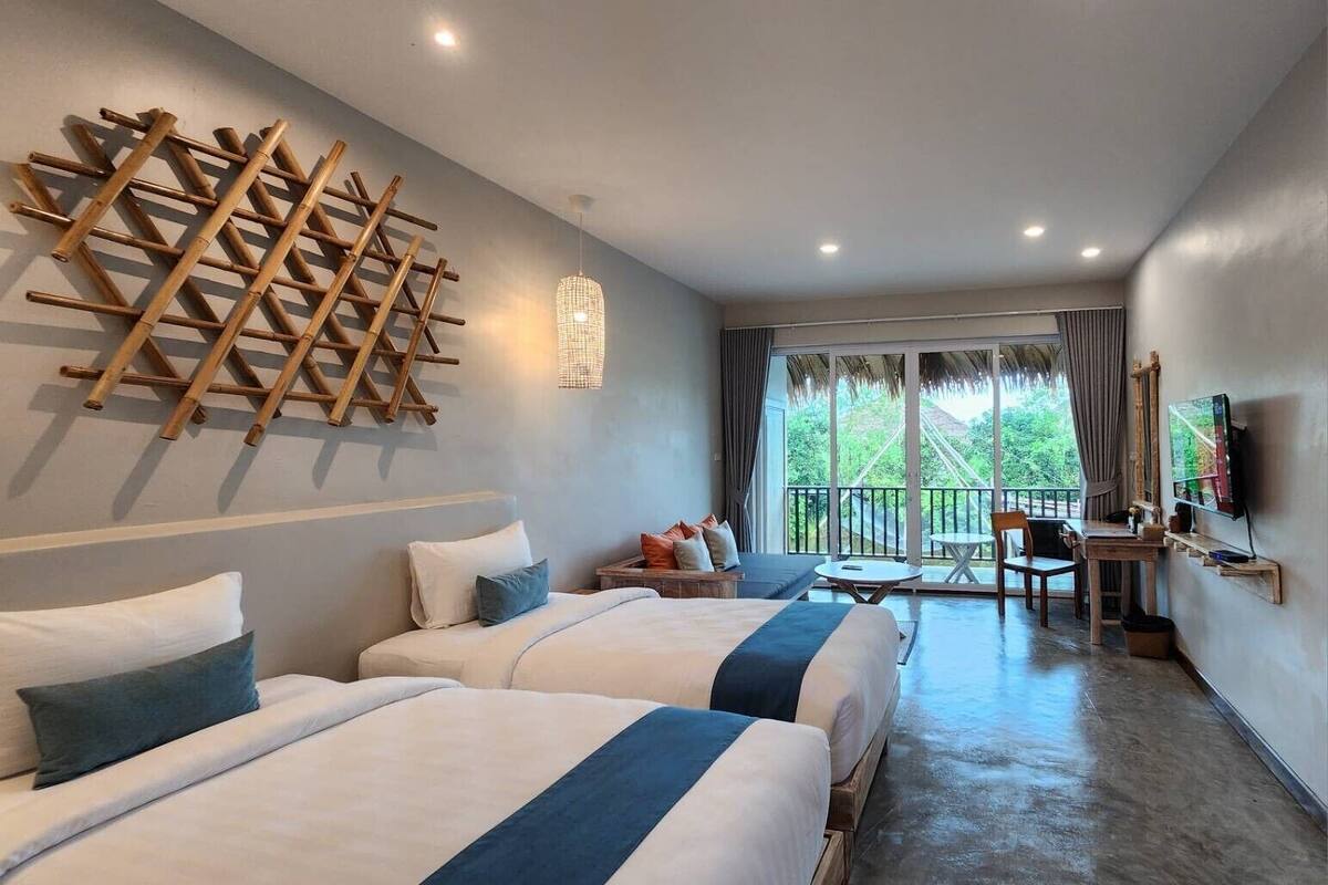 A hotel room with two beds, a balcony, a desk, and a TV.