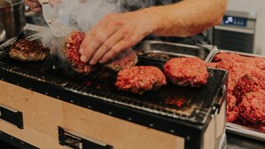 Henkilö grillaa hampurilaisia keittiössä, jossa on grilli ja kattila työtasolla.