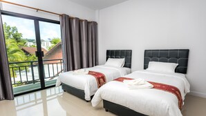 A hotel room with two beds, a balcony, and a view of greenery and buildings. - Mr. T Kamala Room (Kamala)