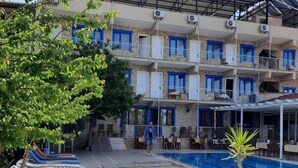 A multi-story hotel with balconies, a swimming pool, and outdoor seating areas.