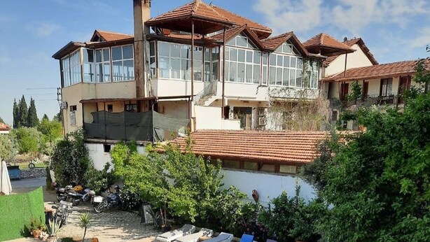 A residential building with a swimming pool, lounge chairs, and a garden area.