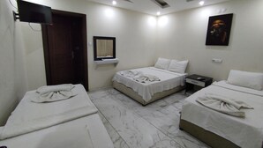 A hotel room with two beds, a small bedside table, a nightstand, a mirror, a TV, and a painting on the wall.
