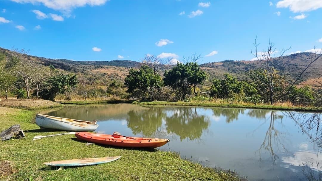 Un lago tranquilo con barcos en la orilla, rodeado de colinas y árboles.