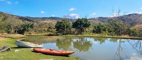 Un lago tranquilo con barcos en la orilla, rodeado de colinas y árboles.
