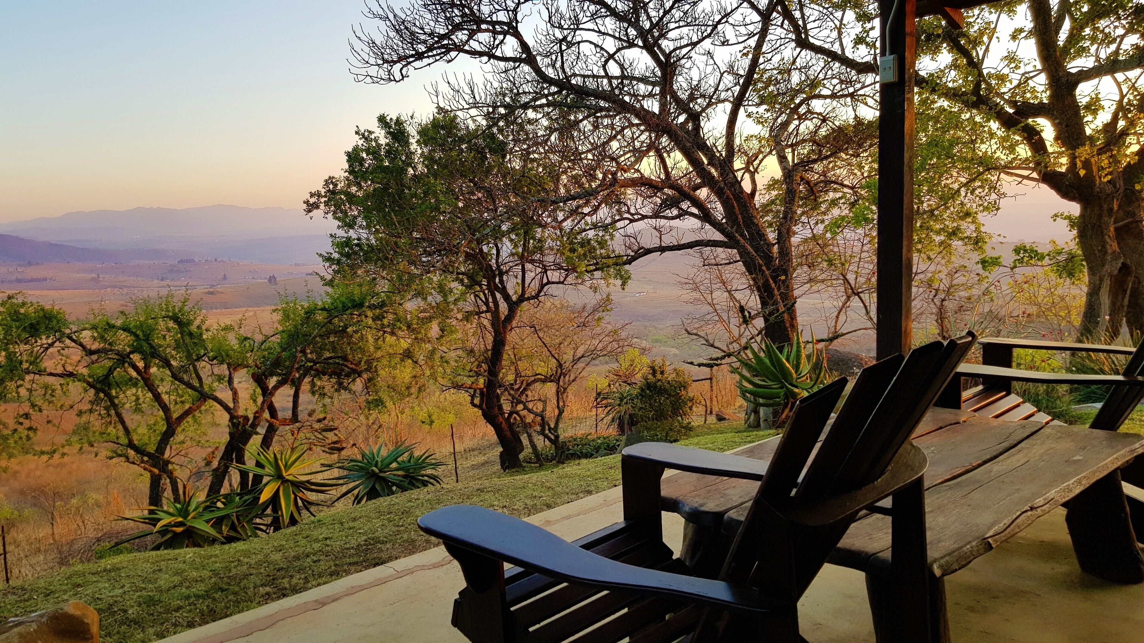 Un banco de madera con vista a un paisaje pintoresco con árboles y colinas lejanas.