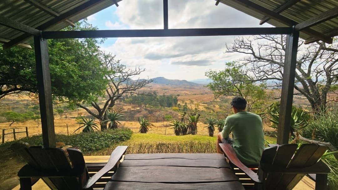 A covered outdoor seating area with a view of a landscape.