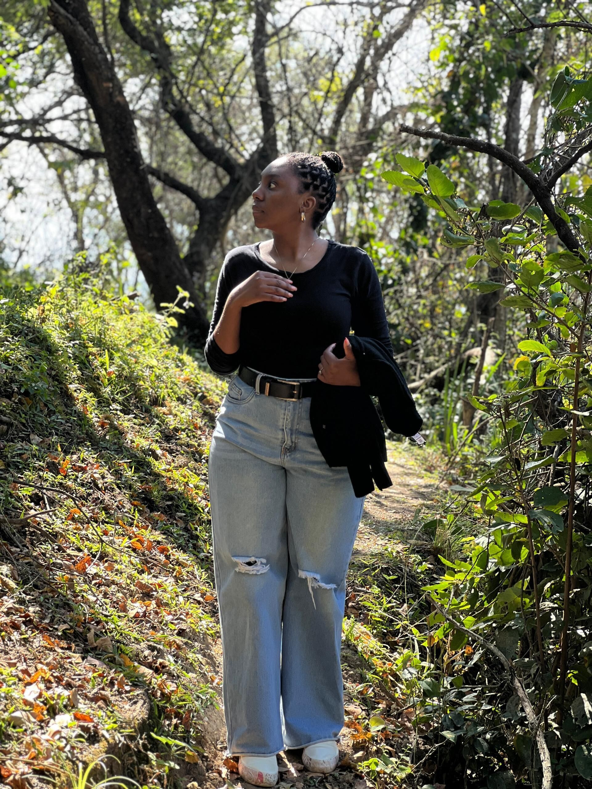 A person standing on a path surrounded by trees and foliage.