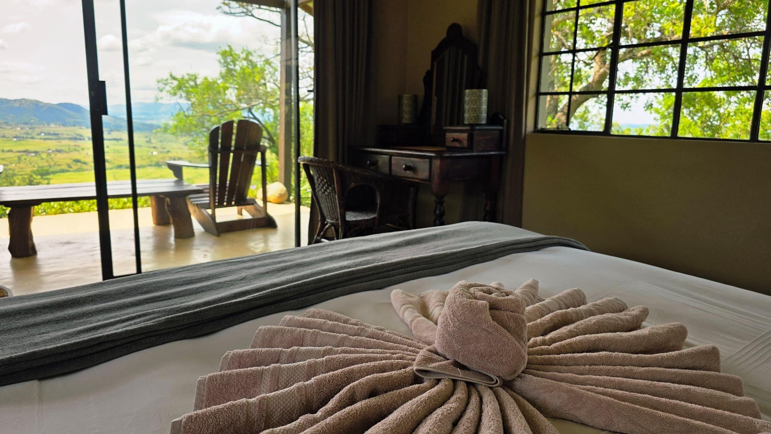 Una habitación de hotel con cama, ventana con vistas al exterior, escritorio y una silla.