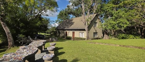 A house with a sloped roof, surrounded by a well-maintained lawn and trees.