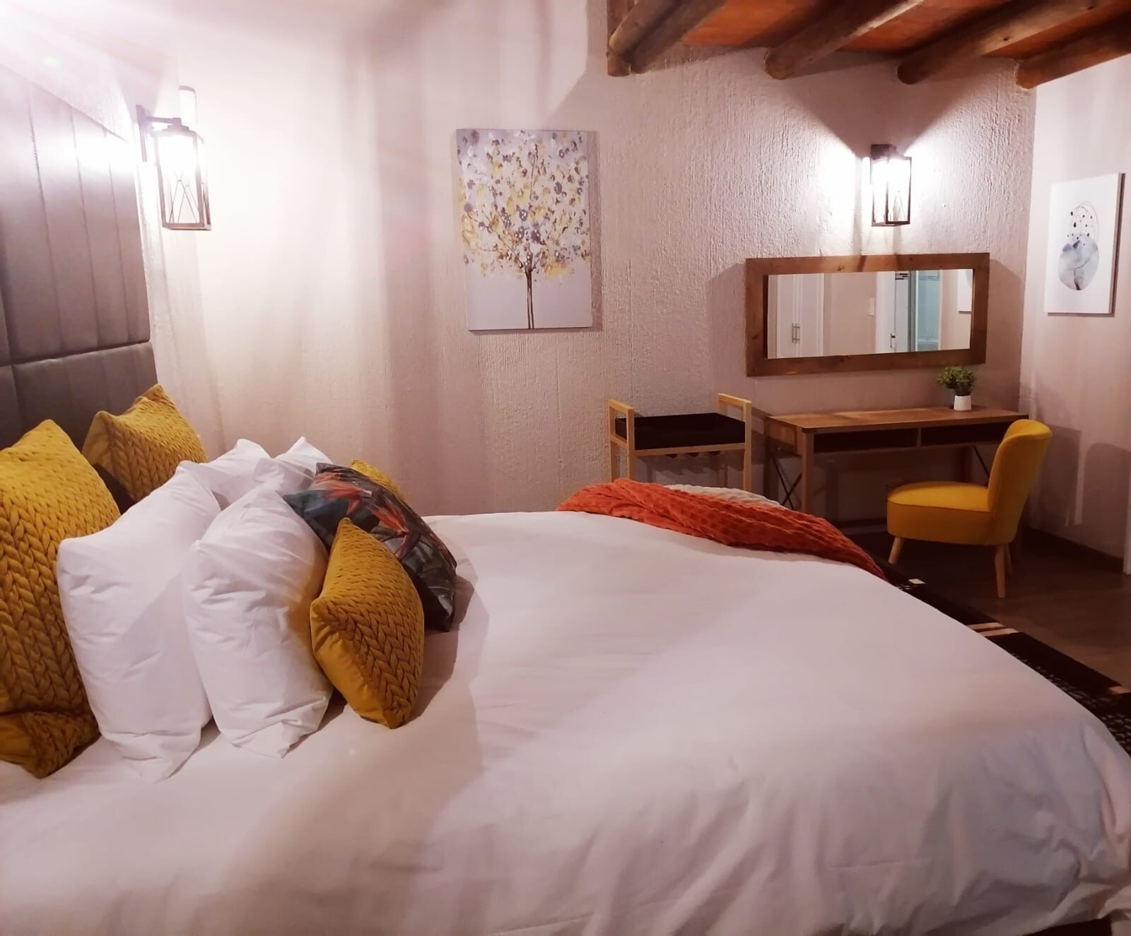 A hotel room with a bed, a desk, a chair, and a mirror.