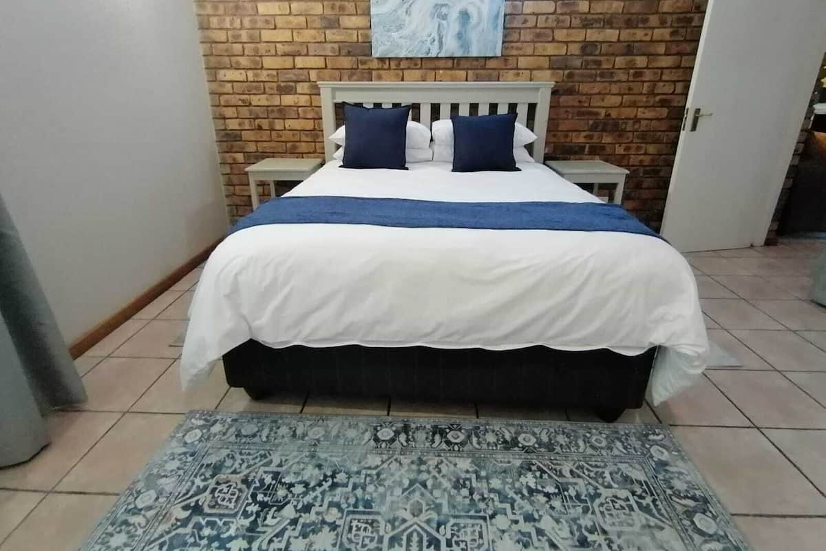 A bedroom with a bed, a nightstand, a wall-mounted painting, and a door.