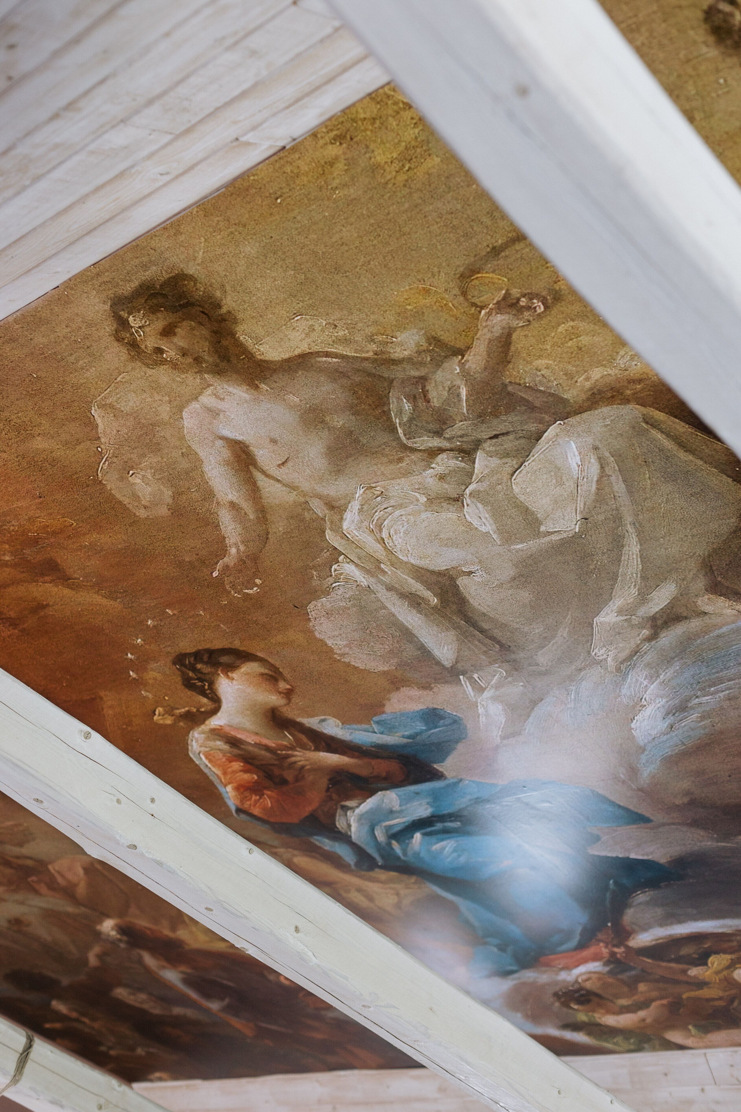 Un fresco en el techo con figuras clásicas y detalles arquitectónicos.