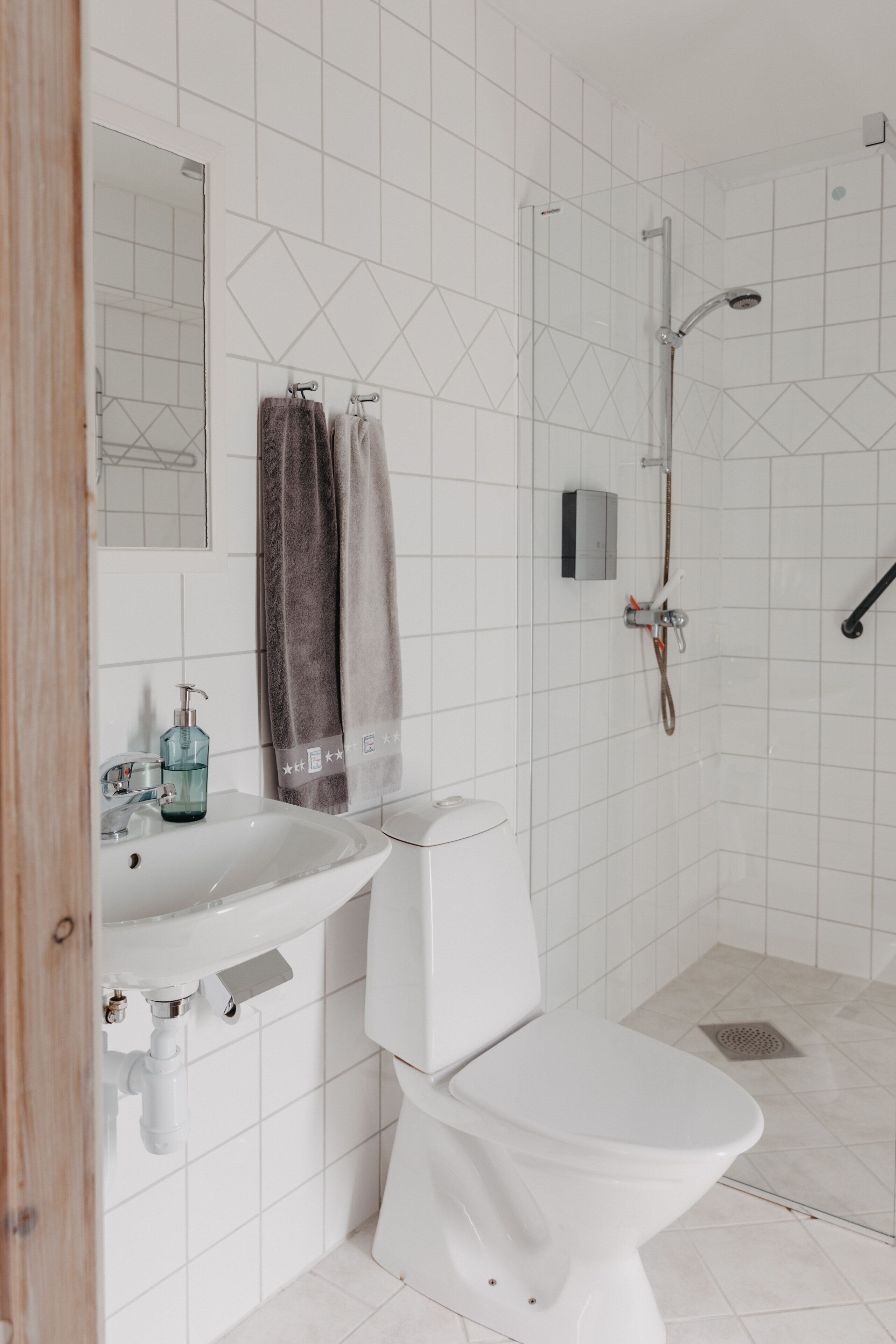Un baño moderno con lavamanos blanco, inodoro, ducha y espejo.