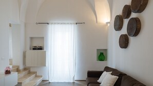 En moderne stue med en brun sofa, en trappe, en grøn vase og kurve på væggen.