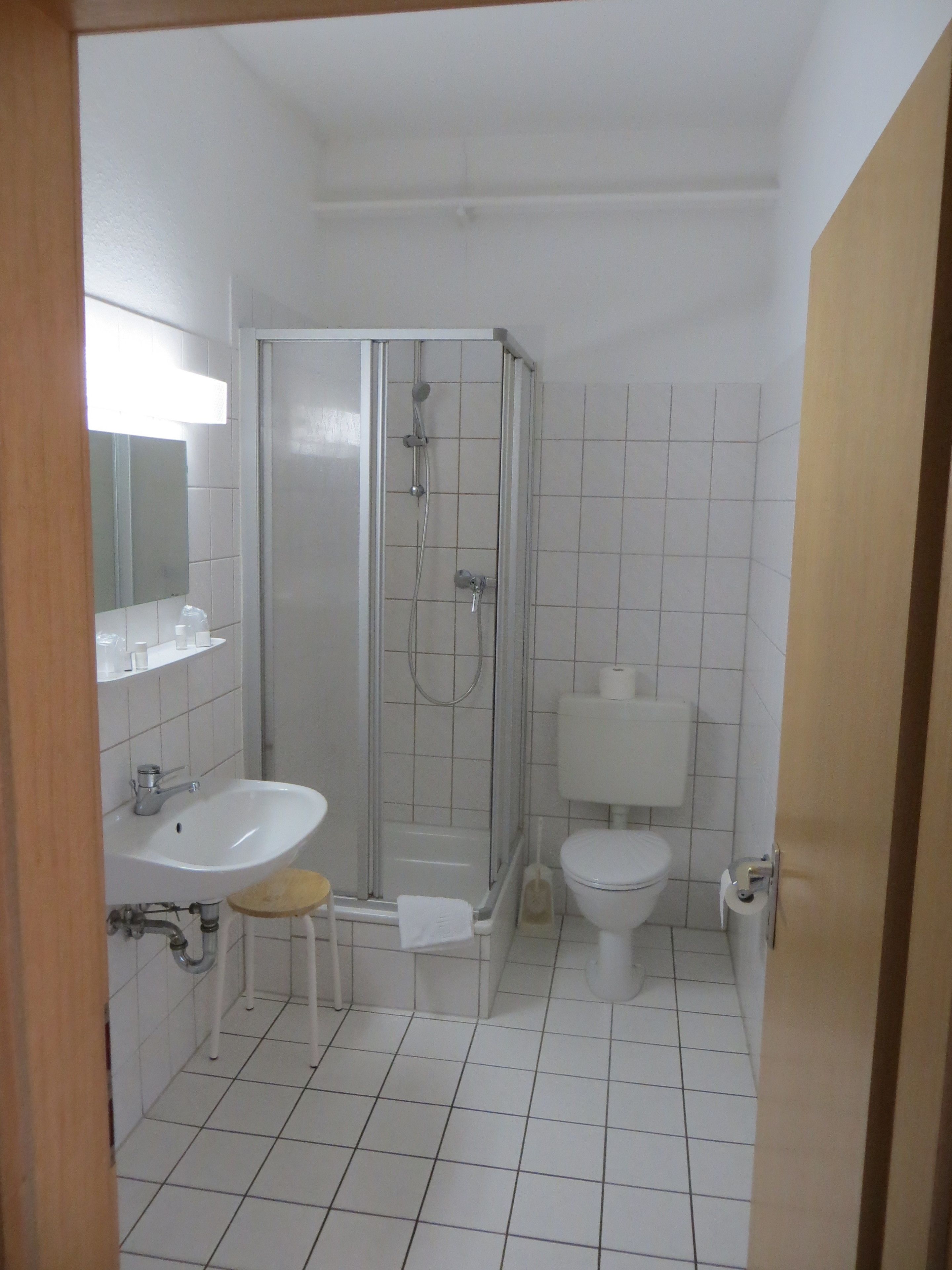 Un baño con ducha, lavabo, inodoro y espejo.