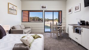Quarto com cama, mesa de cabeceira, janela e vista para uma piscina e árvores.