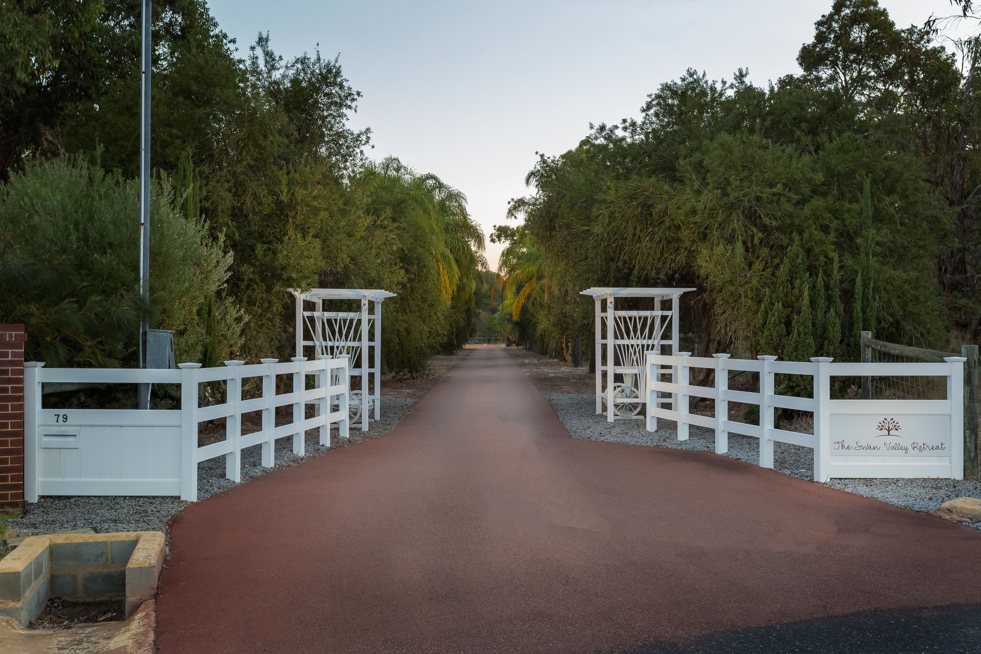 A gated entrance to The Swinn Valley Retreat with a paved path leading through.