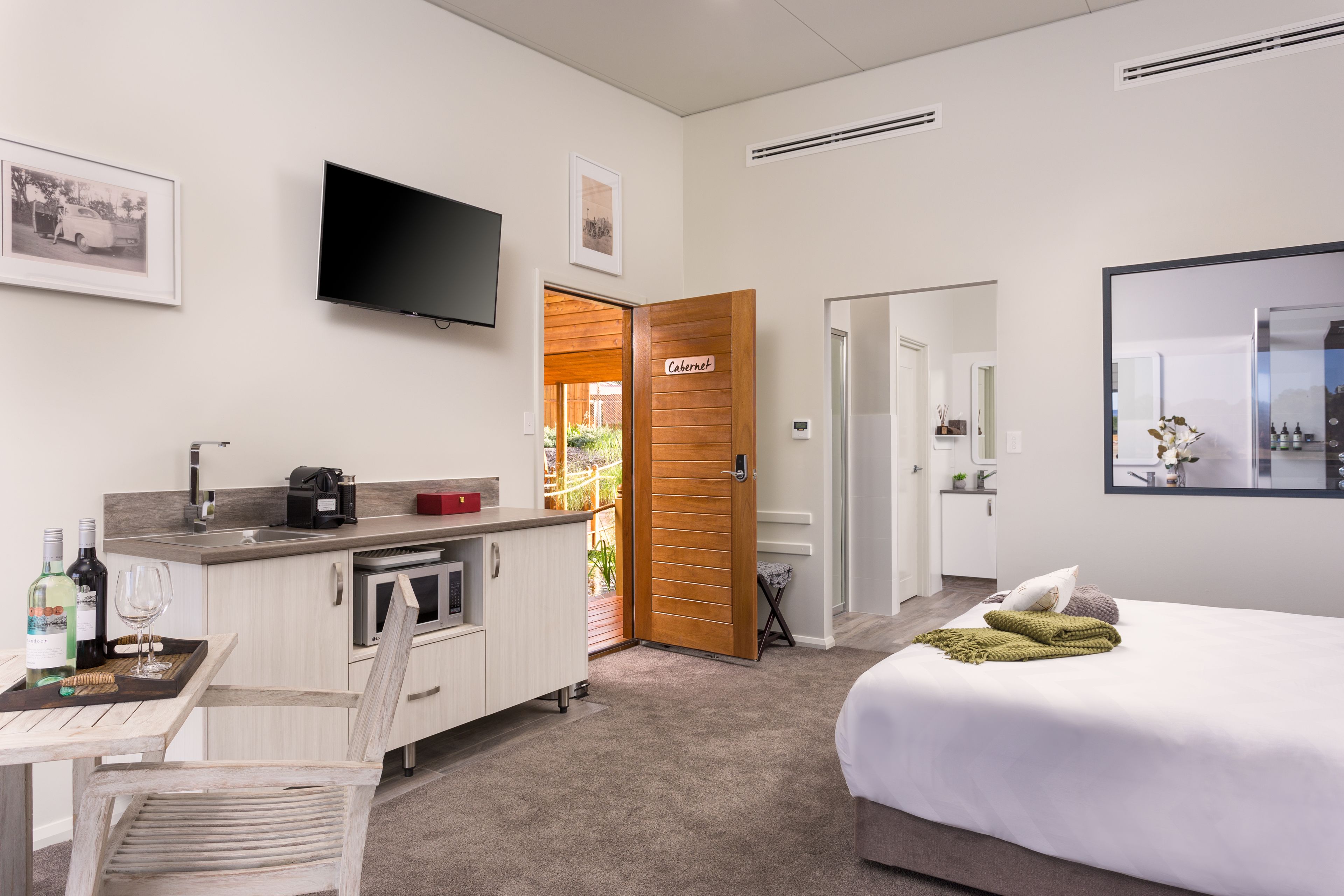 A hotel room with a bed, a desk with a chair, a TV, a kitchen area, and a door labeled "Cabaret".