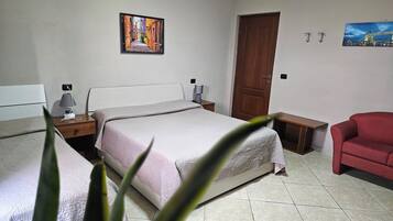 A bedroom with a bed, bedside tables, a chair, a door, and two wall-mounted pictures.