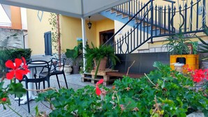 An outdoor patio area with a staircase, potted plants, and outdoor furniture.