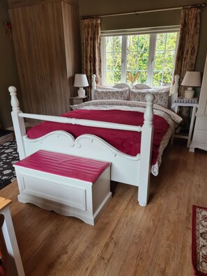 A bedroom with two beds, a window with curtains, a wooden wardrobe, and a bedside table with a lamp. - Brookvale Bed & Breakfast (Wellingtonbridge)