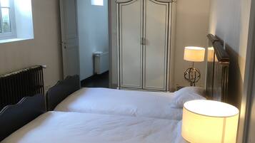 A bedroom with a large bed, a chandelier, a wardrobe, and a bedside lamp.
