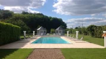 Una piscina al aire libre, sombrillas, sillones reclinables de piscina