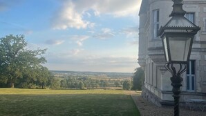 Un grand bâtiment historique, doté d’une tour imposante et d’une pelouse bien entretenue à l’avant.