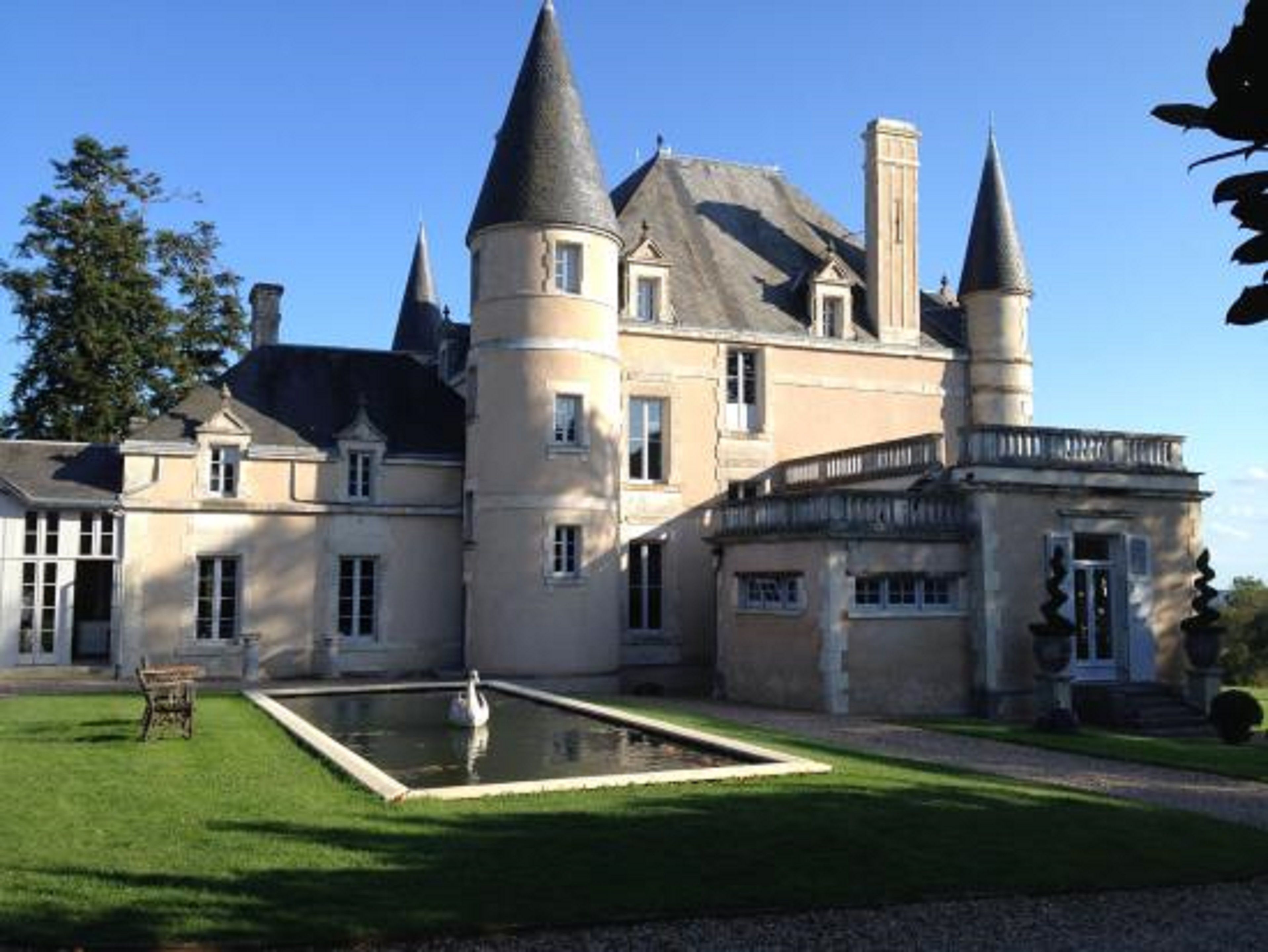 Un grand bâtiment historique doté de nombreuses tours et d’une cour centrale avec une fontaine.