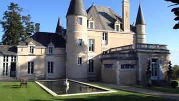 Un grand bâtiment historique doté de nombreuses tours et d’une cour centrale avec une fontaine.