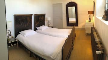 A hotel room with two beds, a large mirror, a dresser, and a radiator.