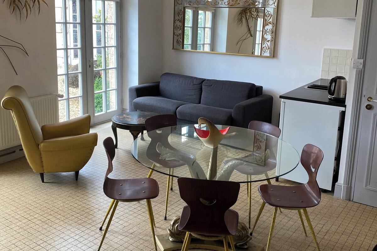 Ein modernes Wohnzimmer mit einem Glastisch, einer Couch und einer Küchenzeile.