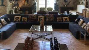 Un vaste salon doté d’un grand plafond en bois, de murs en pierre et d’un grand échiquier servant de pièce maîtresse.