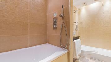 A bathroom with a bathtub, a shower area, and a toilet.