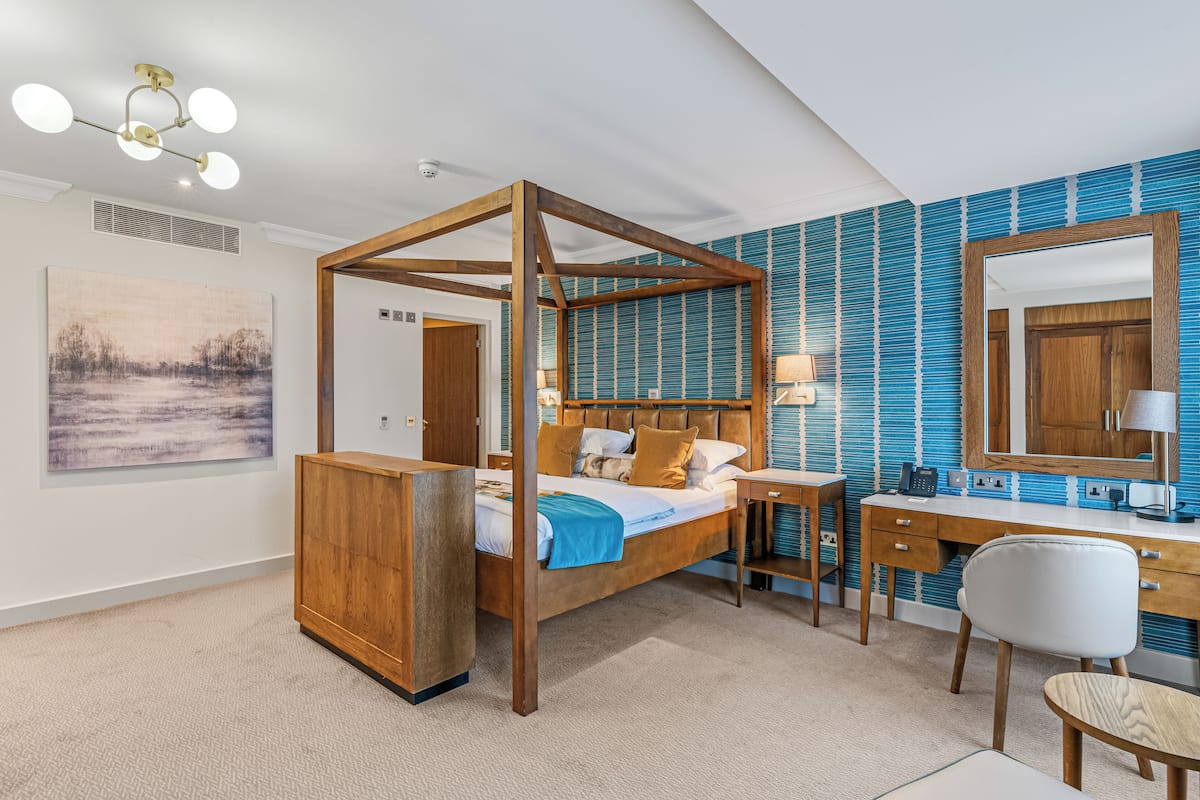 A bedroom with a four-poster bed, a desk, and a chair.